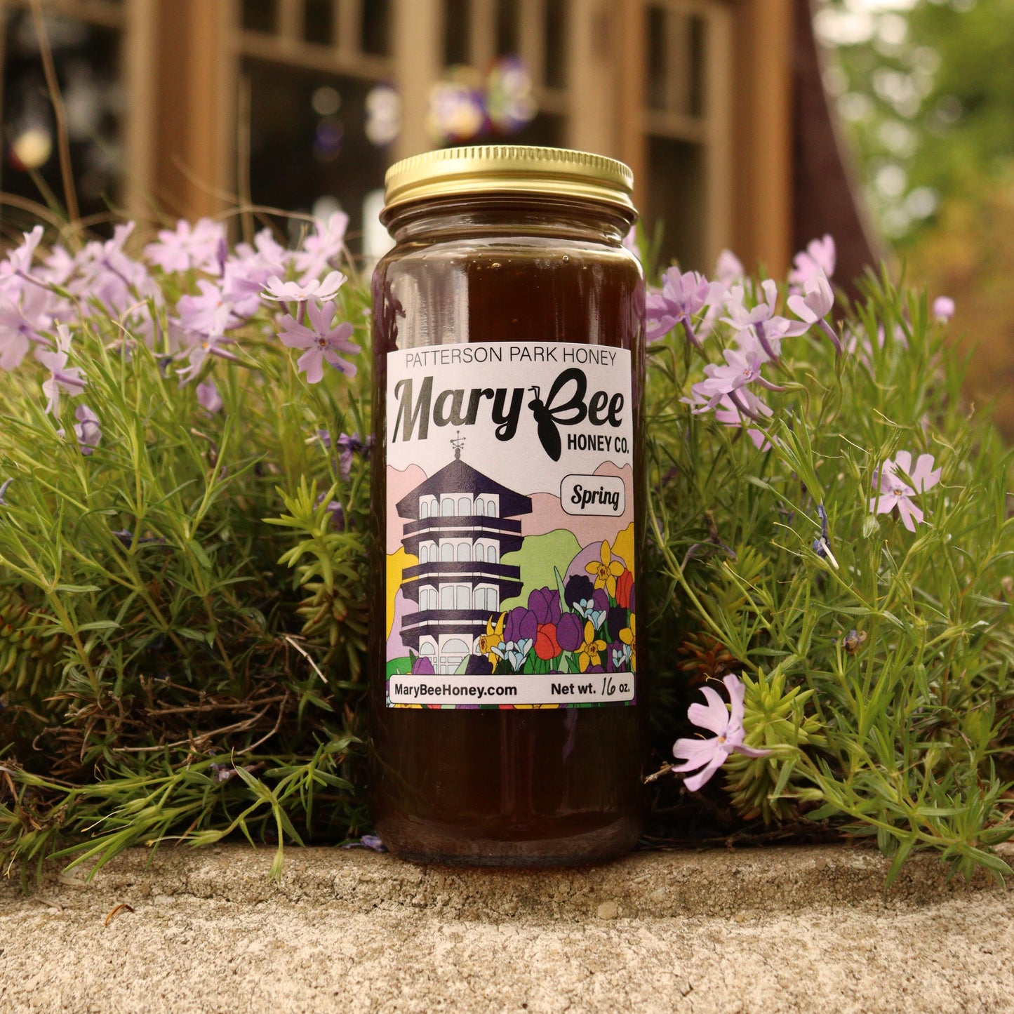 A jar of dark honey with a colorful label sits in front of purple flowers at the Patterson Park Observatory in Baltimore.