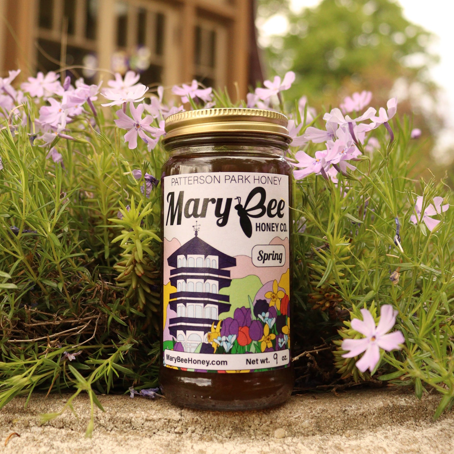 A jar of dark honey with a colorful label sits in front of purple flowers at the Patterson Park Observatory in Baltimore.